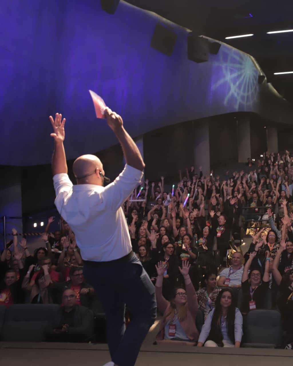 Lucas Veríssimo de costas no palco com plateia lotada de mãos levantadas
